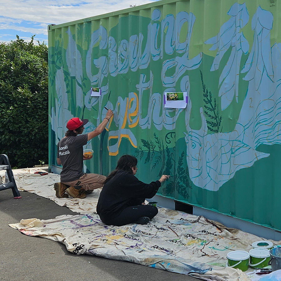 Mentored volunteers painting the Growing Together mural together