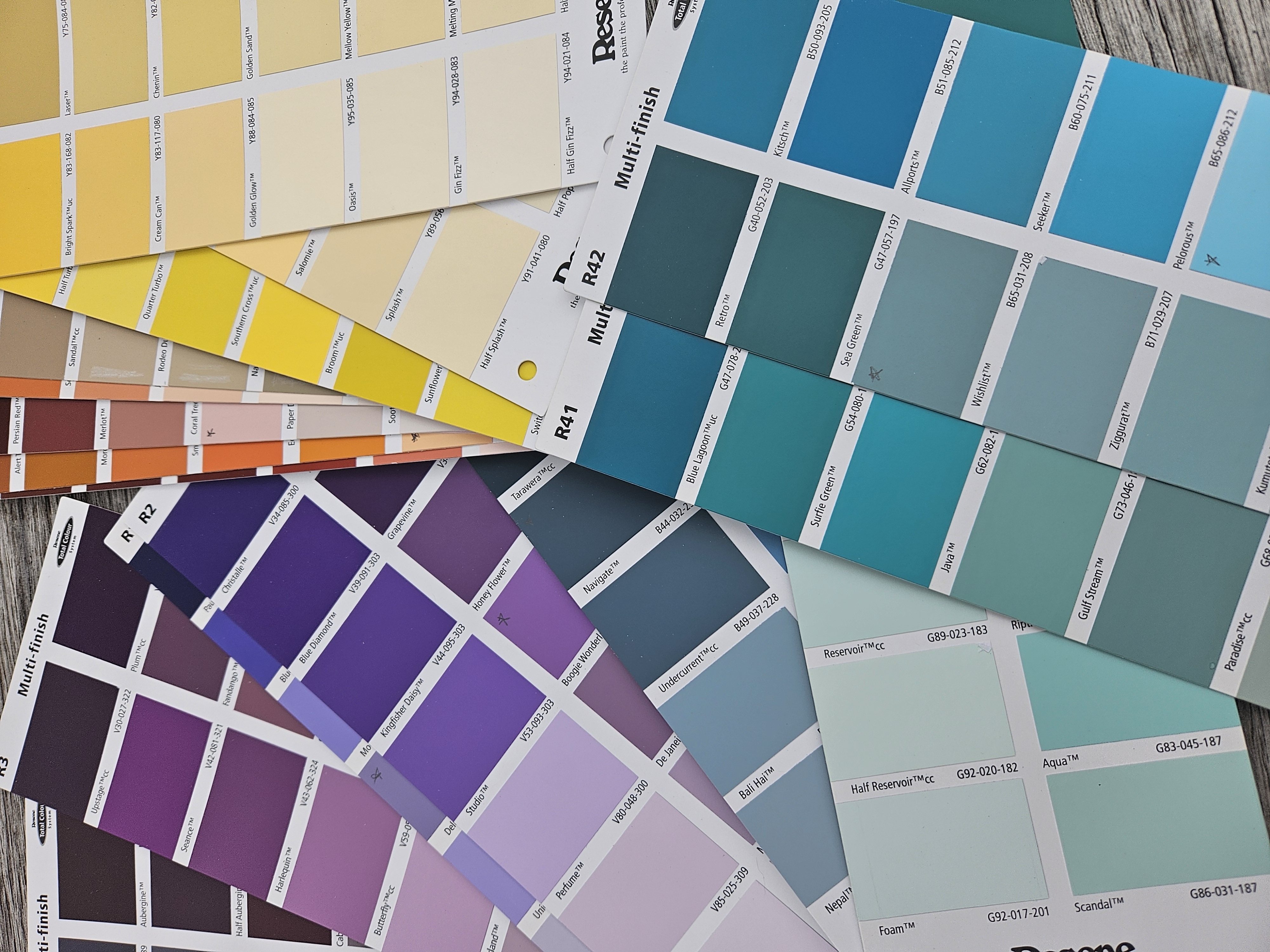 A spread of paint colour swatch cards in yellow, teal and purple tones used to develop a mural's colour palette