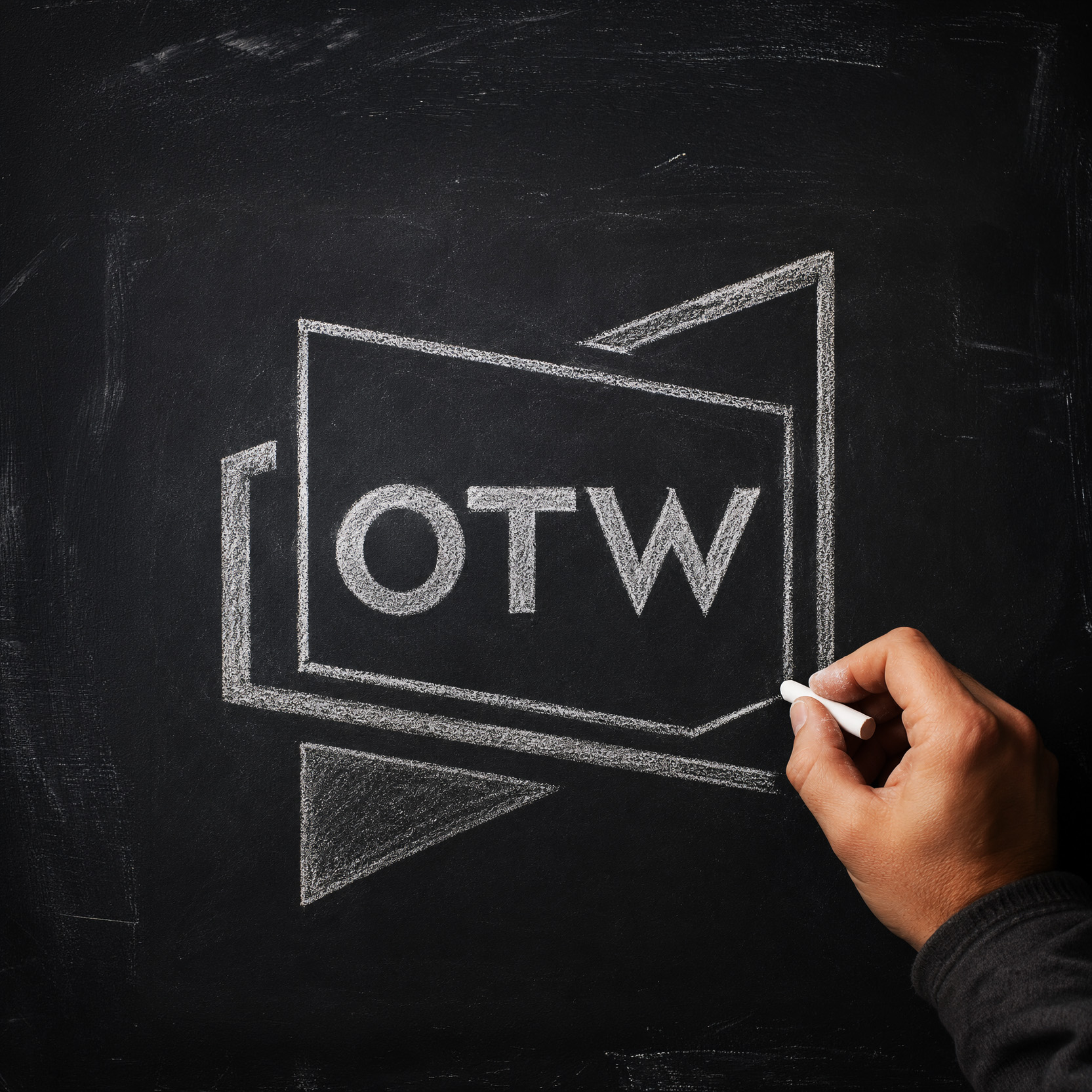 A hand drawing the OTW logo in chalk on a blackboard