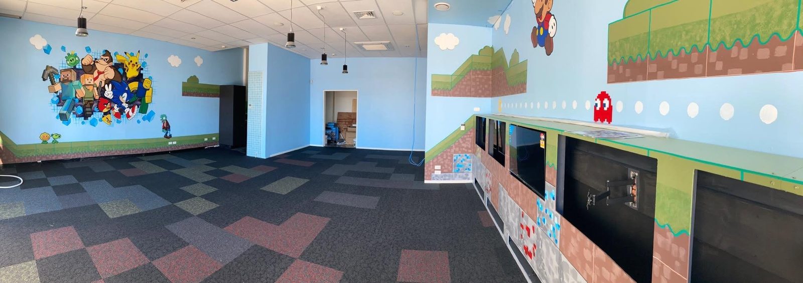 Pixel Party — wide view of the gaming room with the character mural and play equipment
