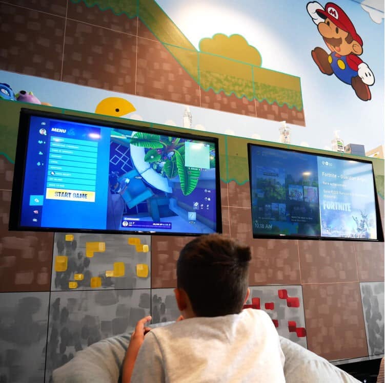 Pixel Party — guests at a gaming station with the mural visible behind them