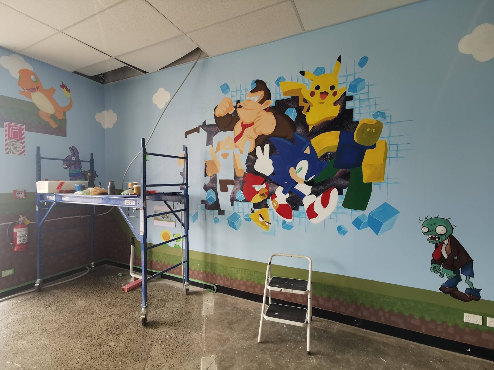 Pixel Party mural in progress — character outlines being painted on a ladder