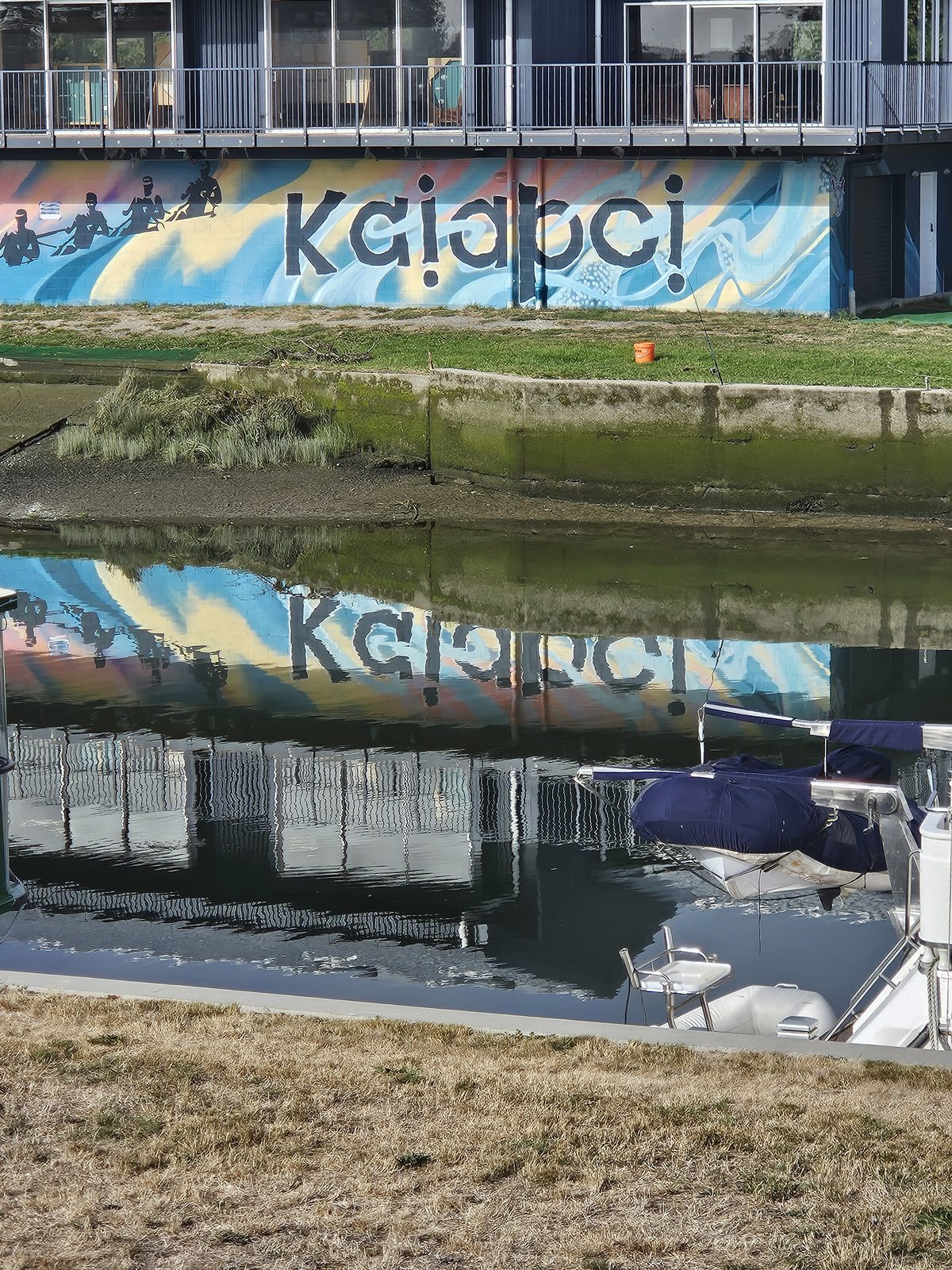 Pulling Together mural — finished view of the rowers and 'Kaiapoi' lettering reflected in the river