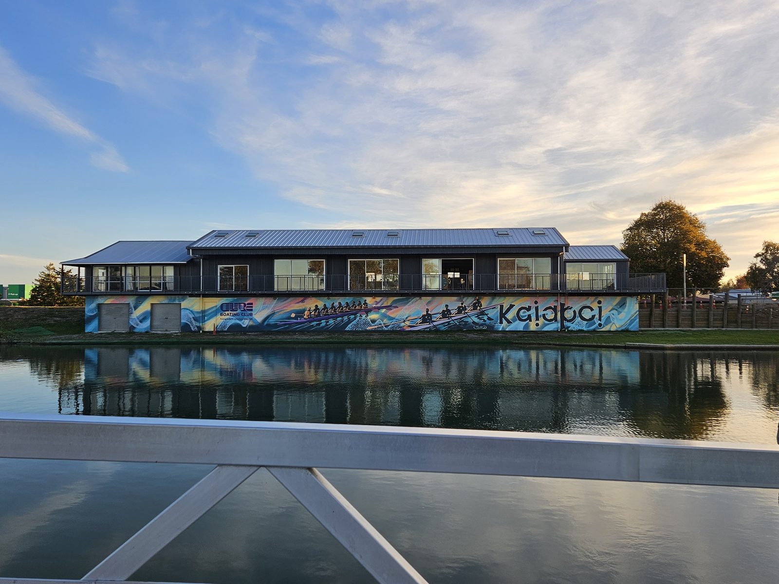 Pulling Together mural — wide view of the clubrooms from the riverside path