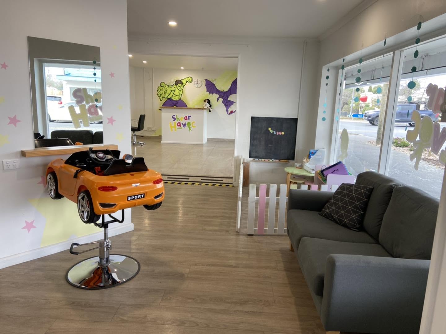 Shear Havoc mural — salon lounge area with an orange kids' car chair and characters on the walls