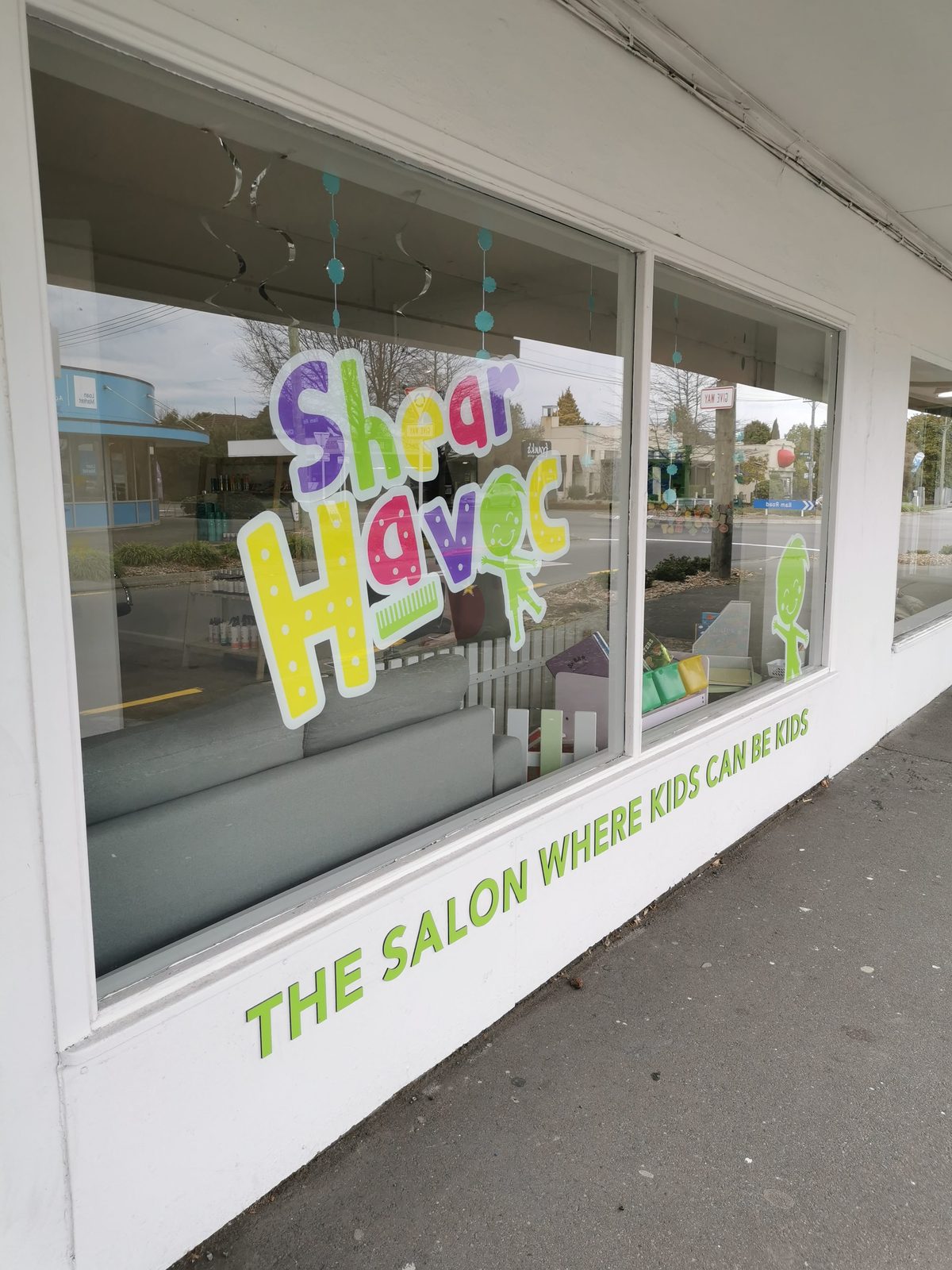 Shear Havoc shopfront window with 'The salon where kids can roar' signage
