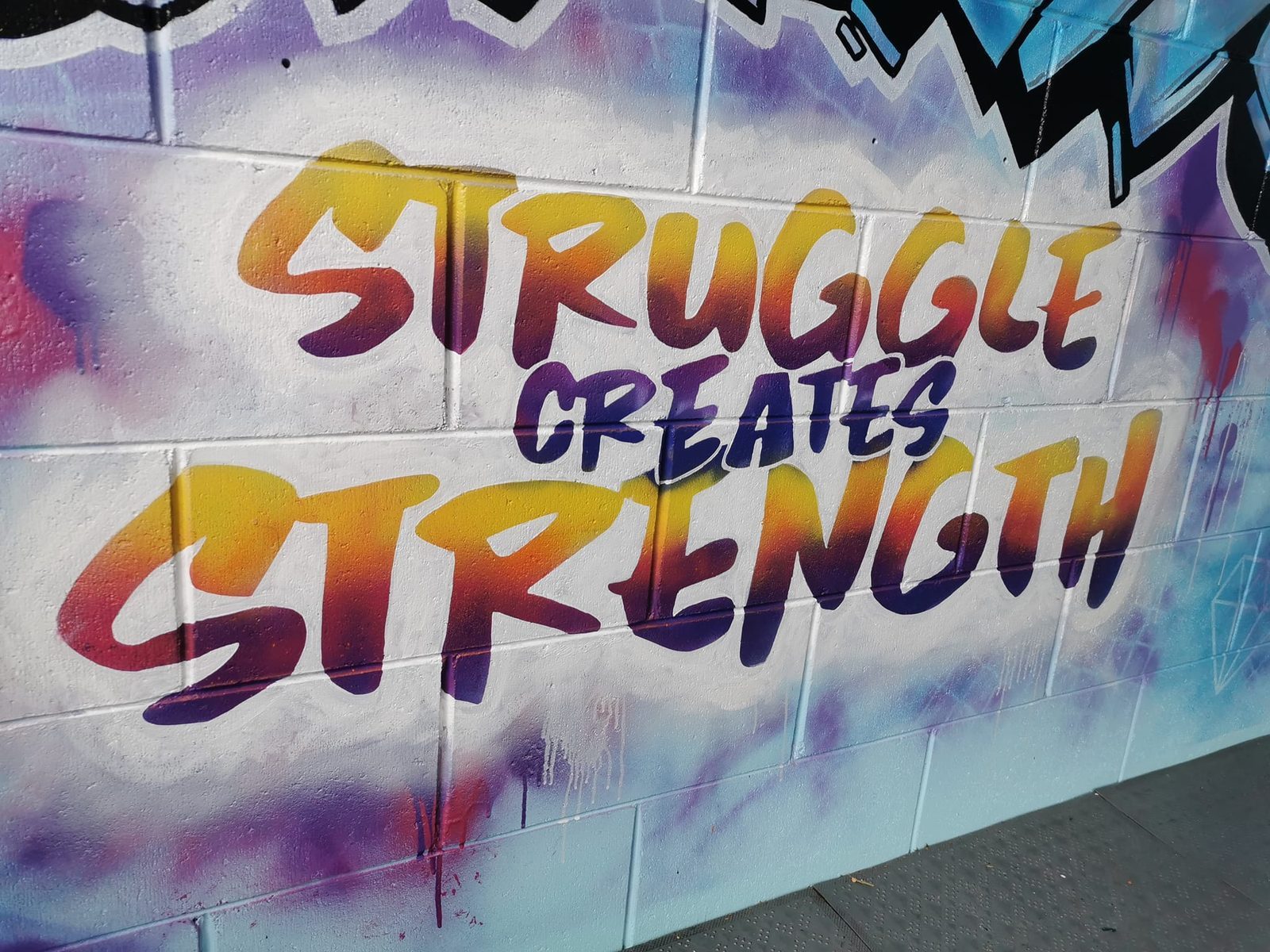 You Rock mural — finished 'Struggle creates strength' lettering in blue and purple graffiti style