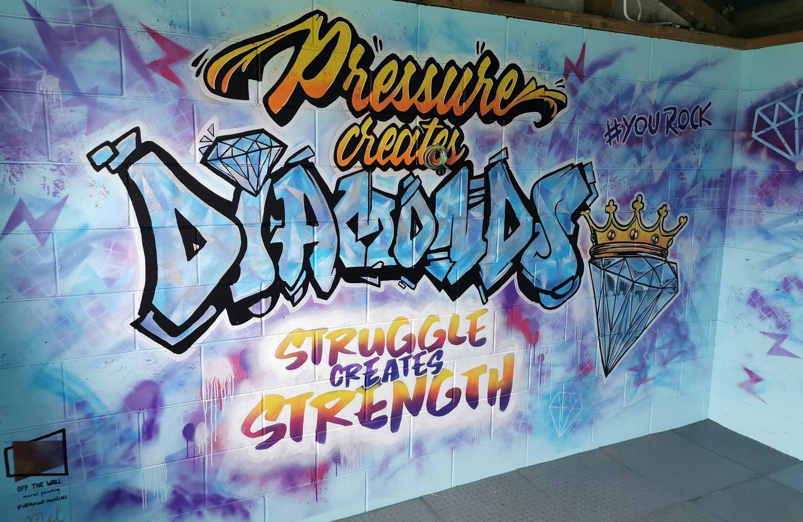 You Rock mural — finished 'Pressure creates diamonds, struggle creates strength' design on the Riddell Gym wall