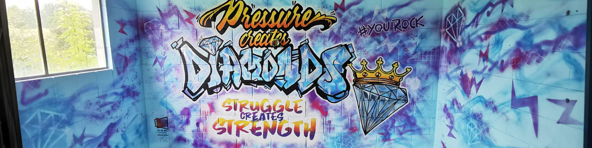 You Rock mural — wide view of the graffiti-style 'Pressure creates diamonds, struggle creates strength' lettering wrapping around the gym's corner walls