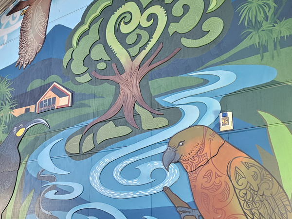 Around The Tree mural detail — stylised native tree with koru-pattern leaves, a winding stream and native birds, Rangiora Borough School
