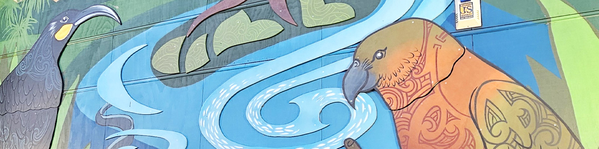 Around The Tree mural detail — a huia and a kākā with tā moko-style plumage patterns either side of a swirling blue river design
