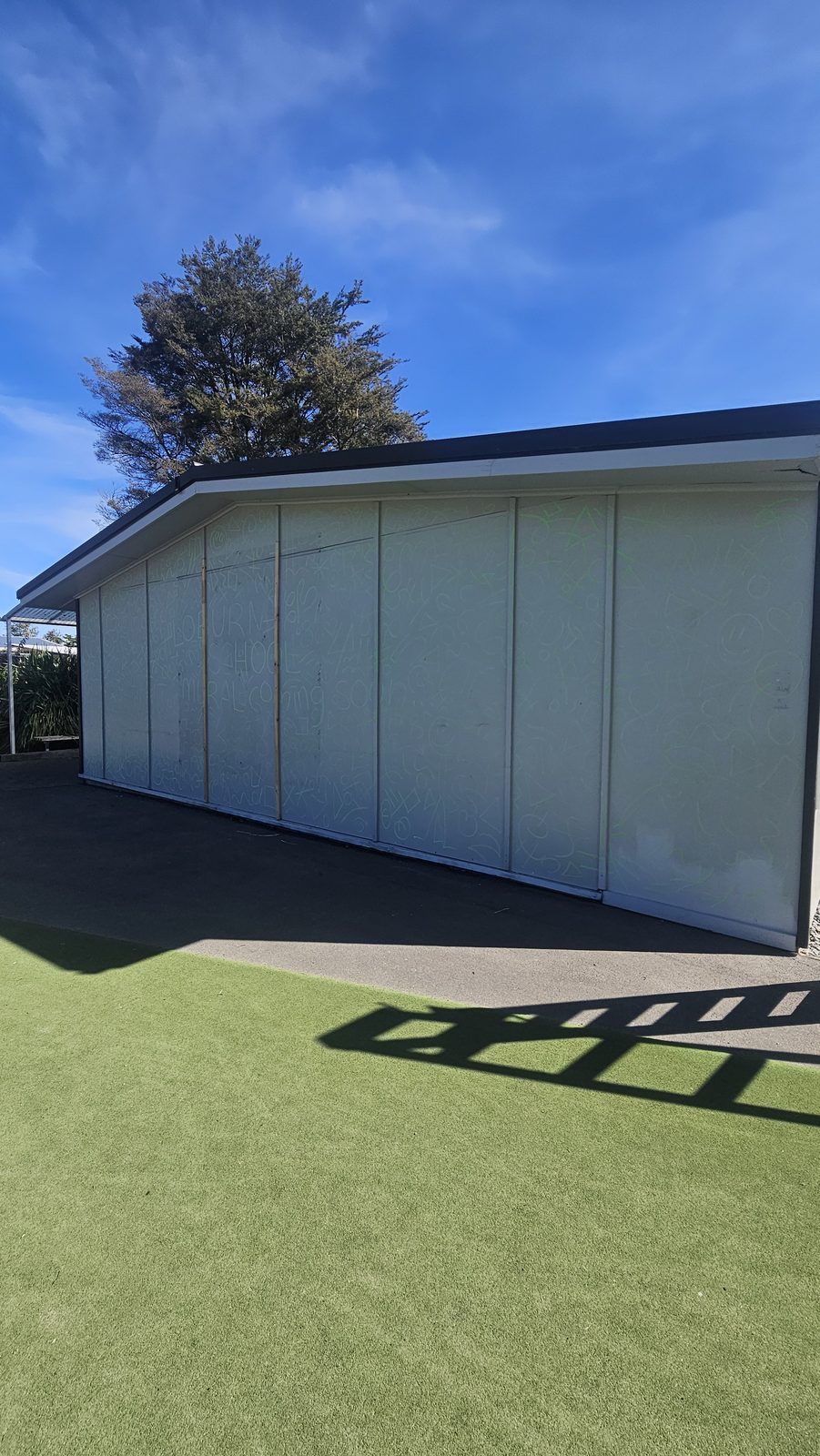 Flock Together — plain building wall before the mural, beside the school's astro-turf court