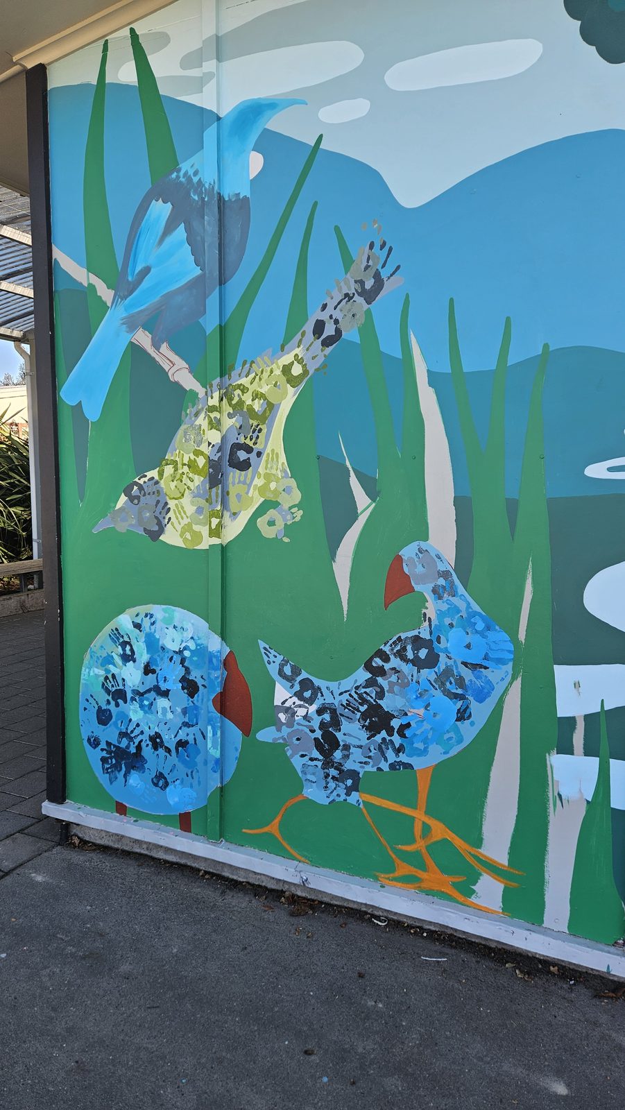 Flock Together mural in progress — two birds blocked in blue and green ahead of detailing