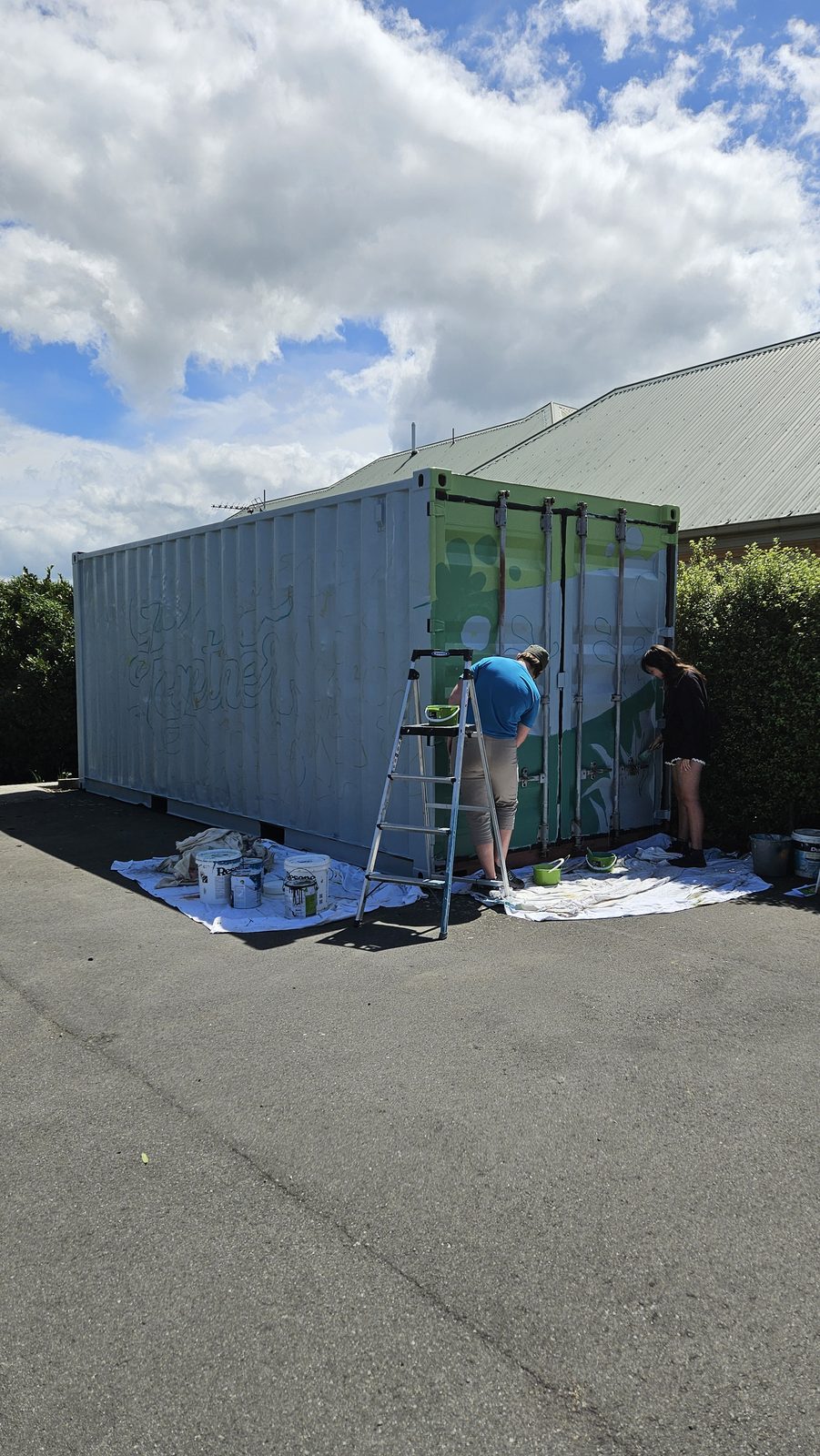 Growing Together mural in progress — green base coat being applied to the container