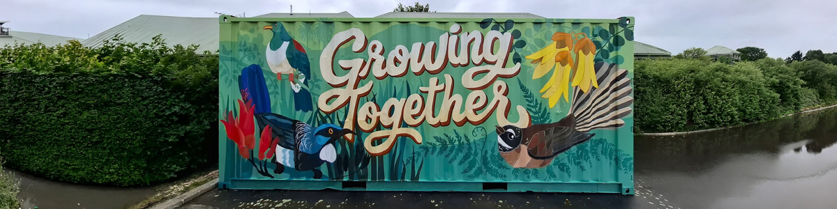 Growing Together mural — full view of the shipping container reading 'Growing Together' with native birds and kōwhai flowers, Chris Ruth Centre