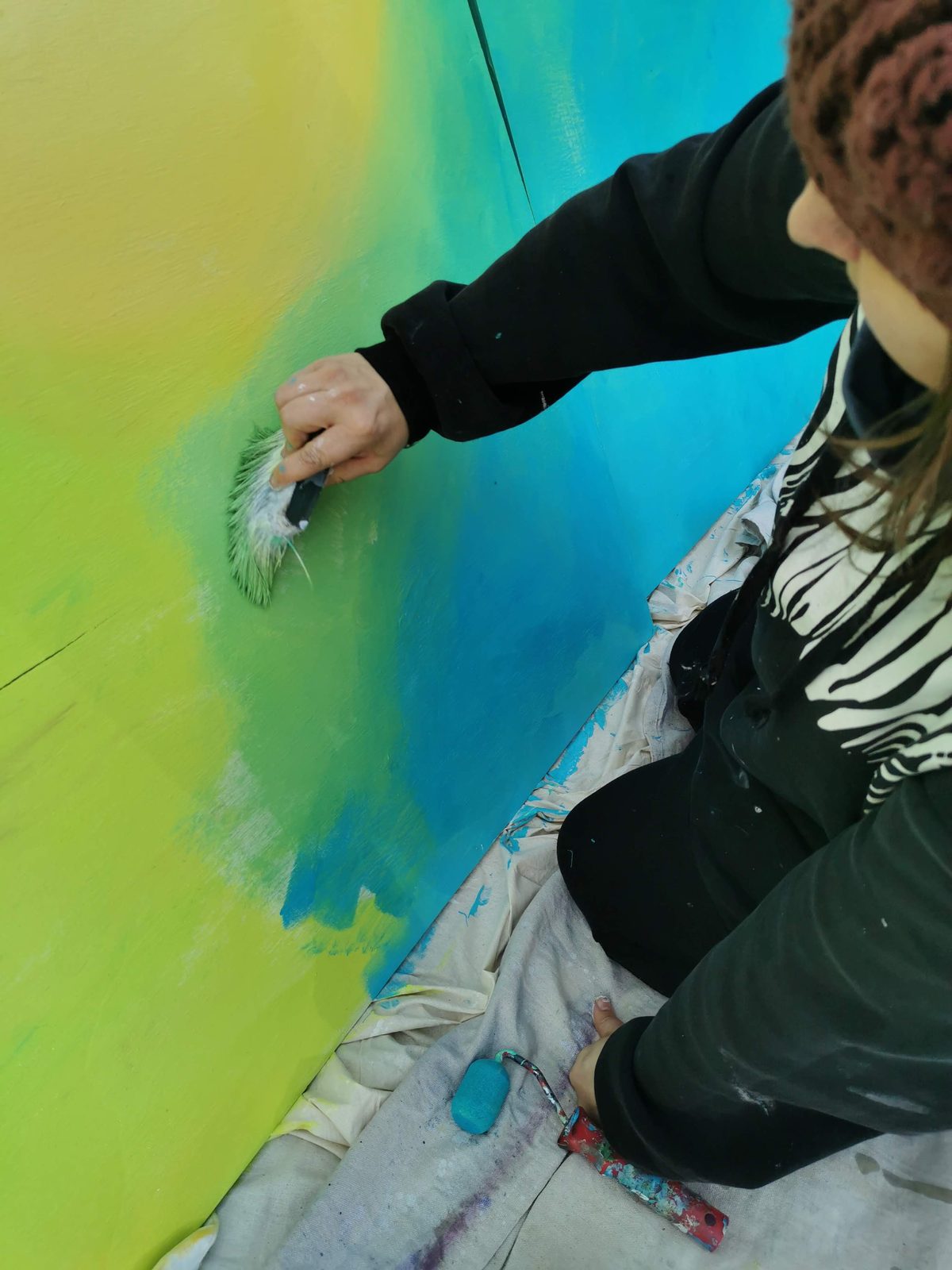 Natures Playground mural in progress — close-up of teal paint being applied to a panel