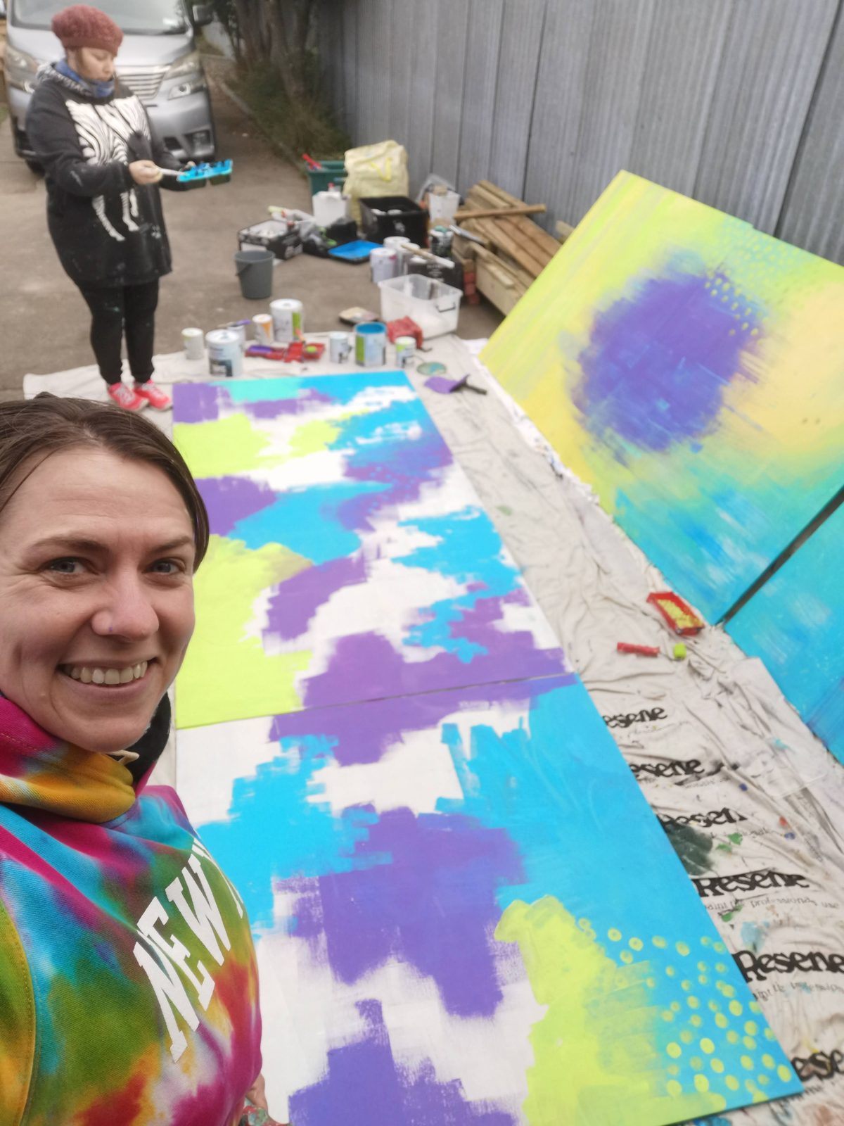 Natures Playground mural in progress — two panels laid flat outdoors with the abstract background underway