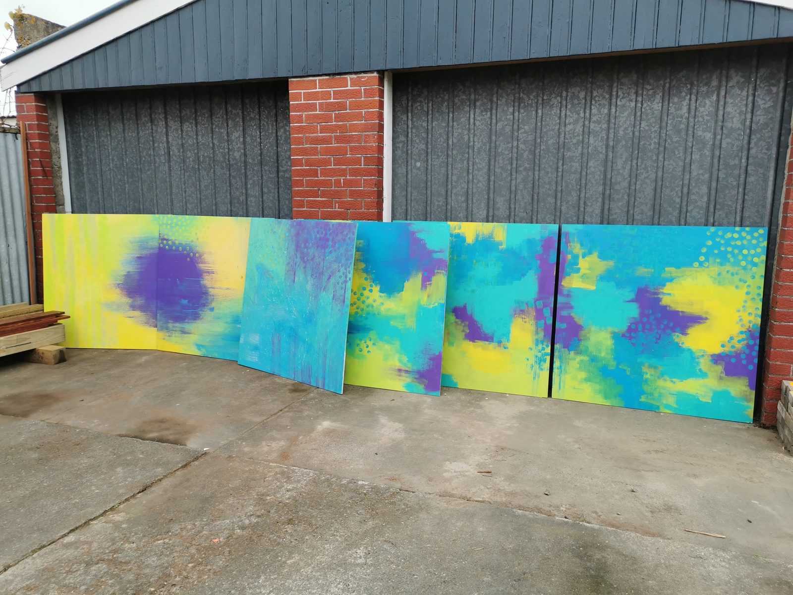 Natures Playground mural in progress — two panels with the yellow, teal and purple gradient background finished