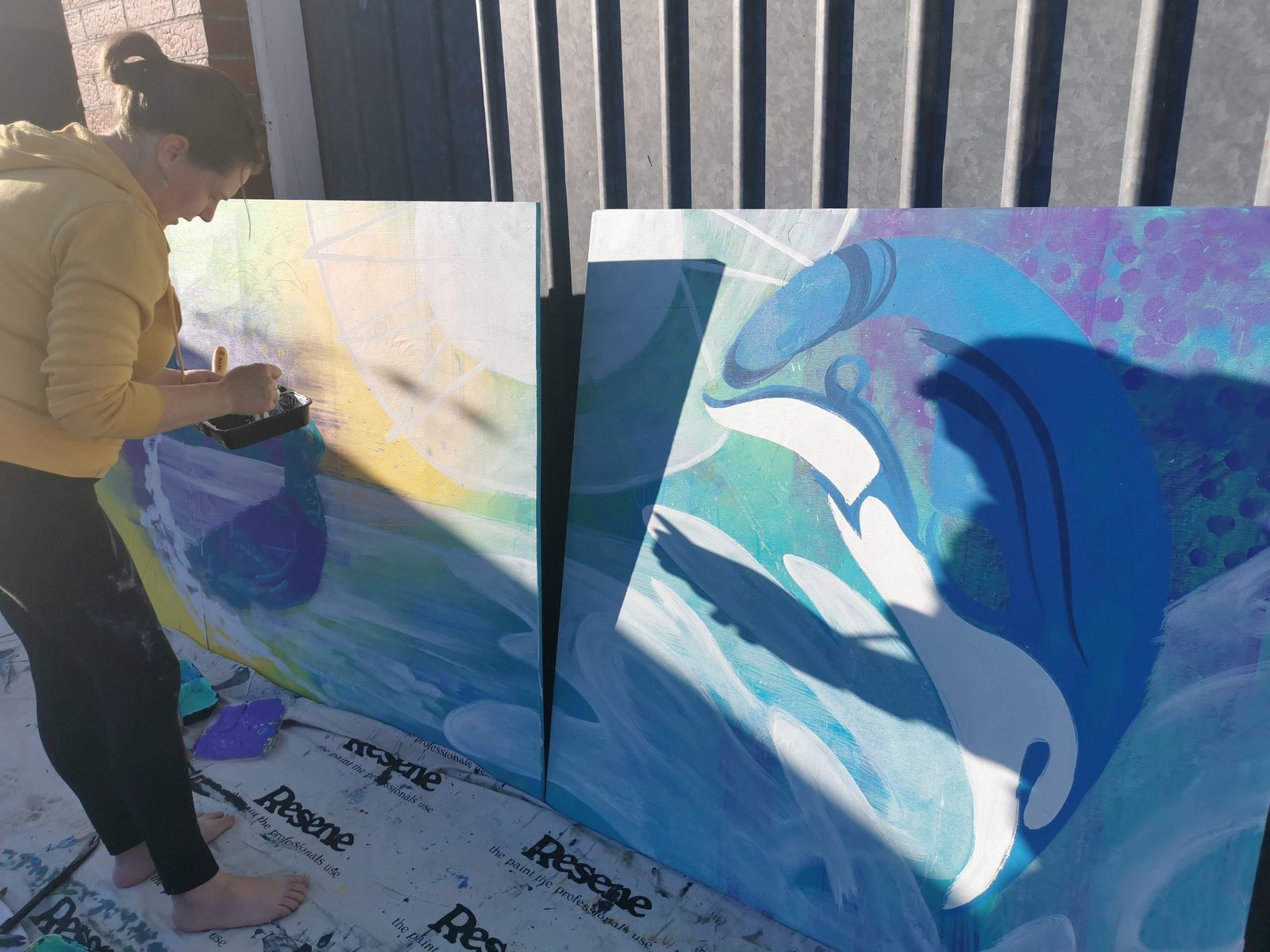 Natures Playground mural in progress — comparing the two bird and dolphin panels outdoors