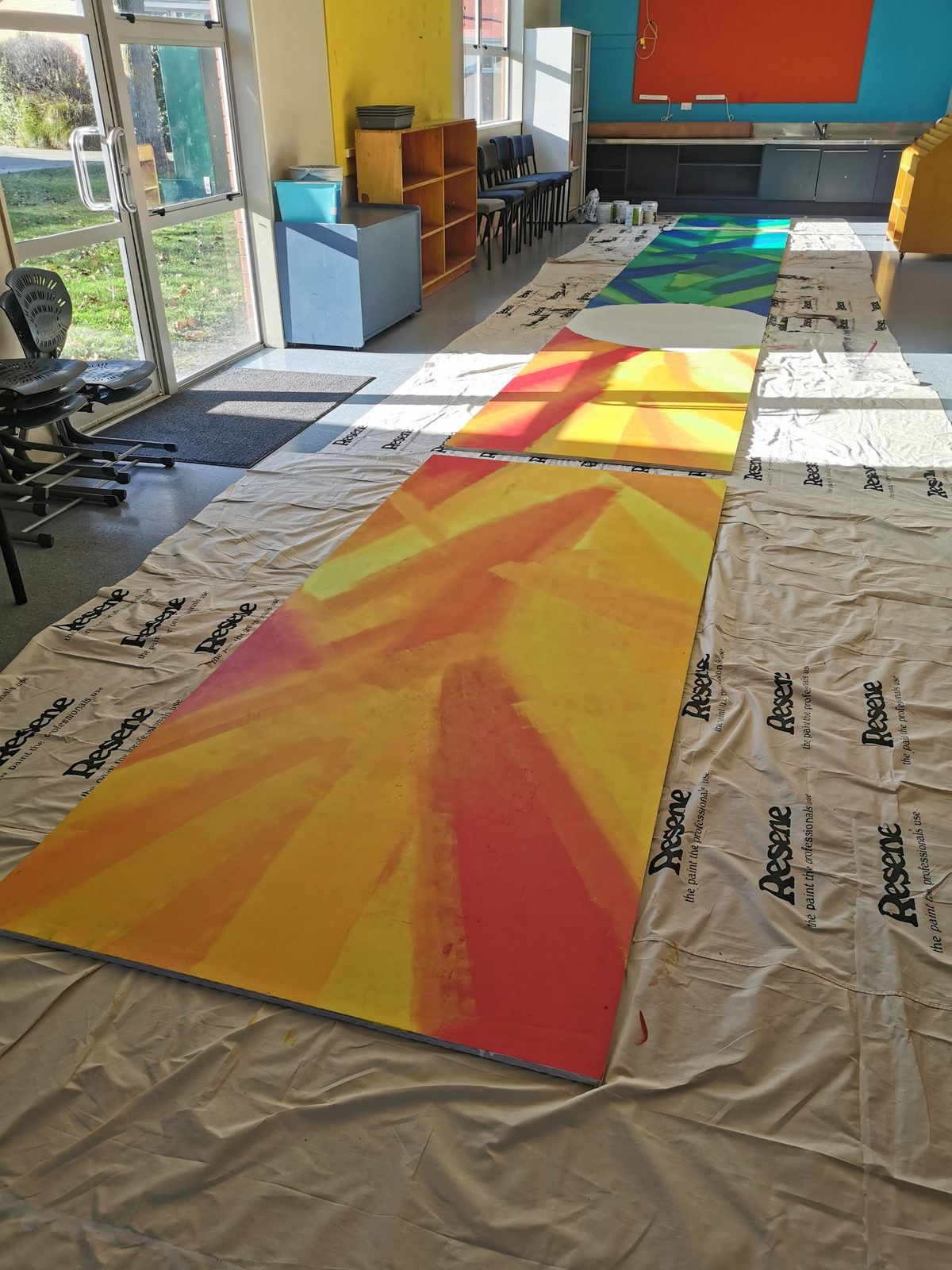 Our Stars — an orange and yellow sunburst panel painted on the floor