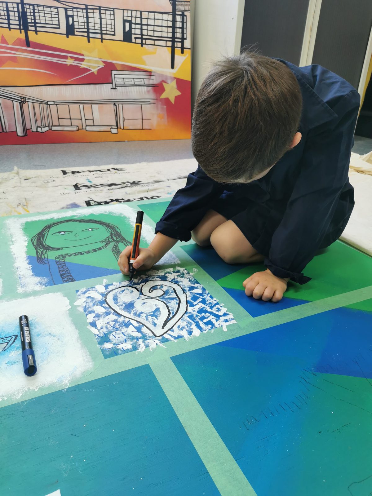 Our Stars — a student painting a small panel design on the ground