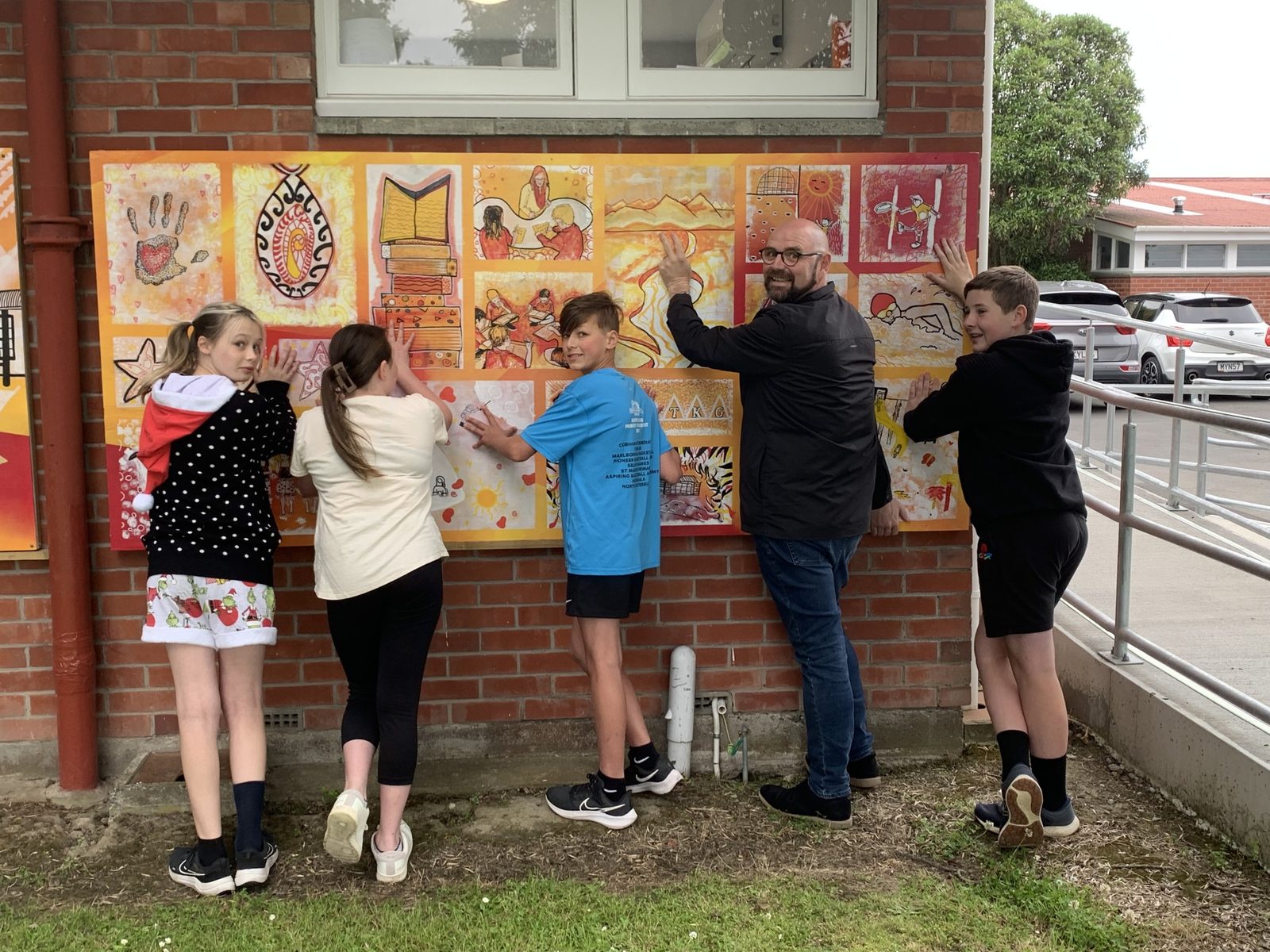 Our Stars — students and a volunteer painting individual panels on the school wall