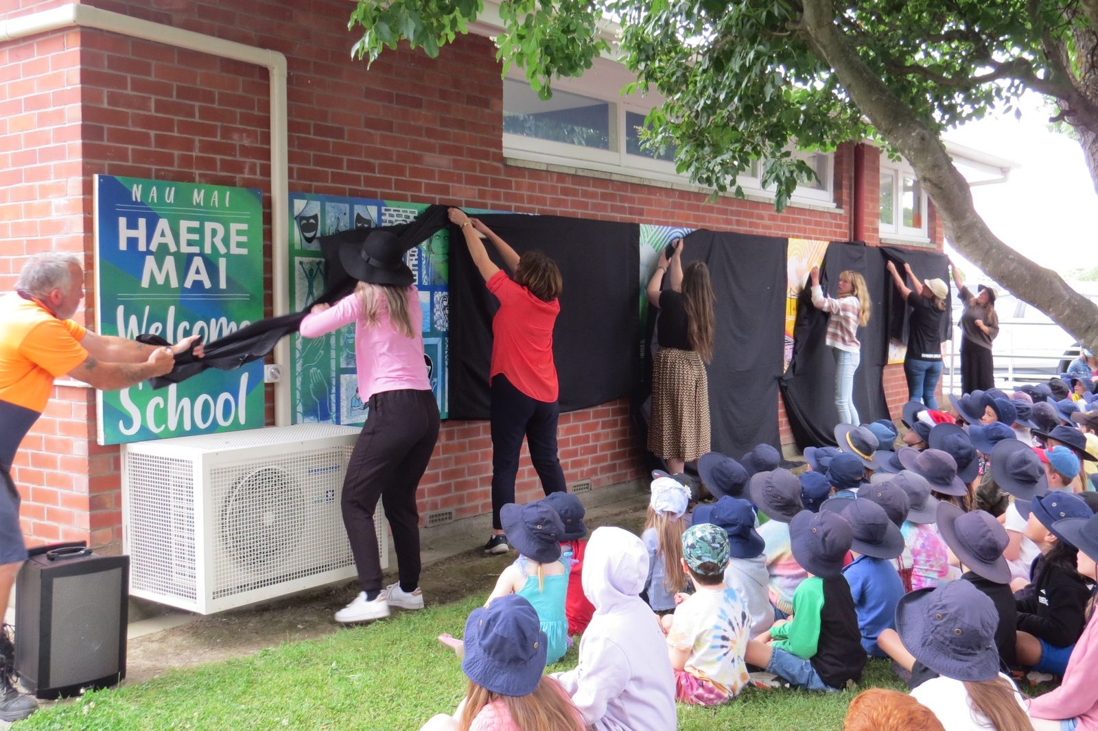 Our Stars — Mel addressing students seated outdoors for the mural unveiling
