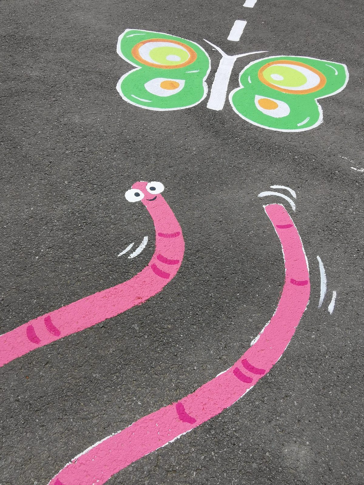Playtime Bugs — a butterfly and wavy worm trails painted on the asphalt