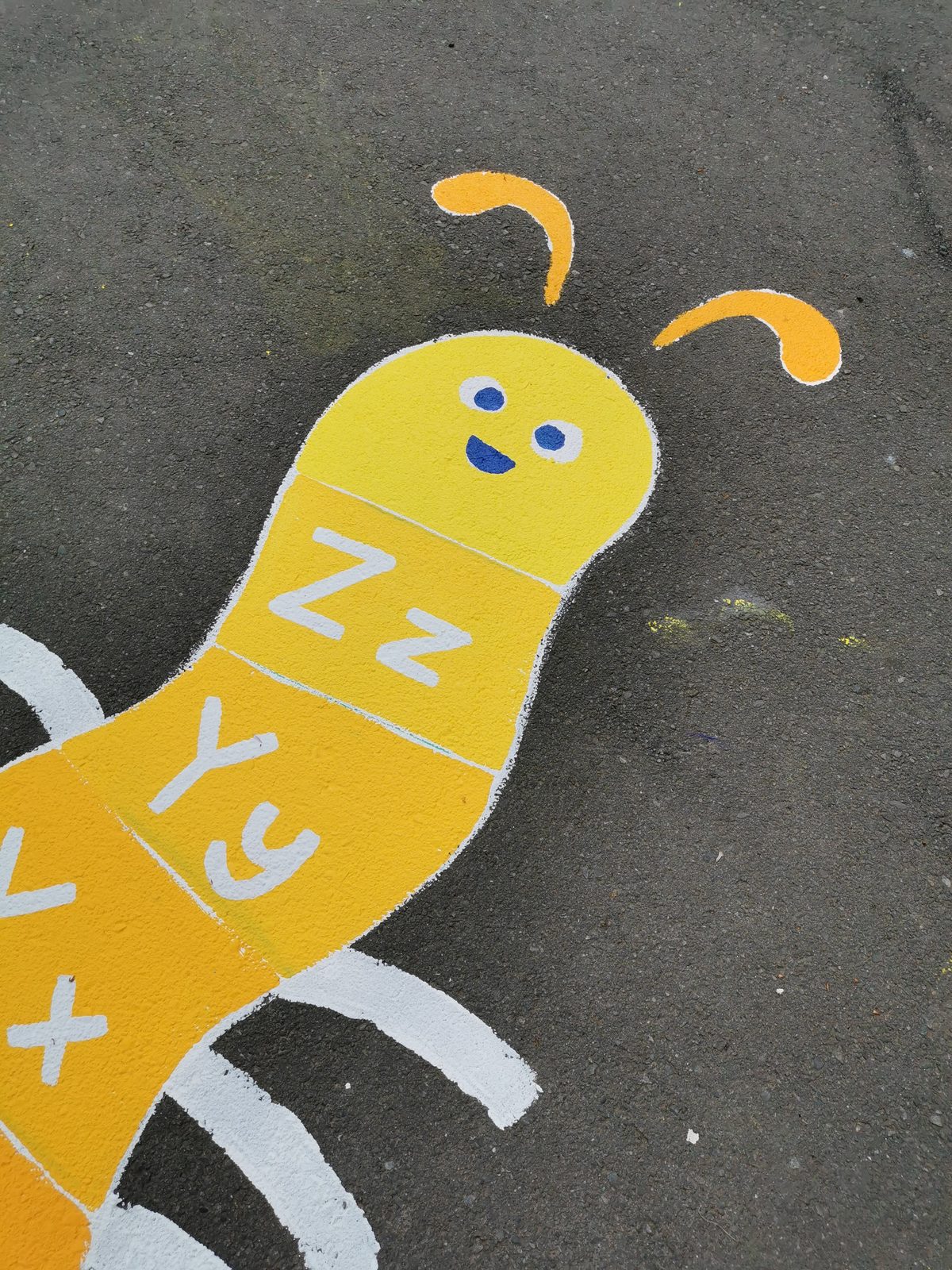 Playtime Bugs — a yellow alphabet caterpillar game painted on the asphalt