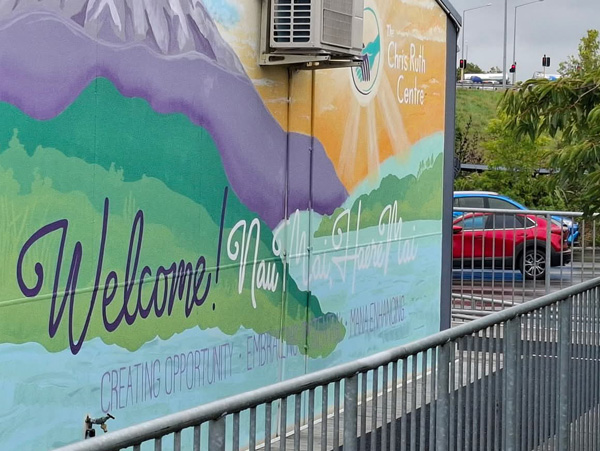 Turangawaewae mural — purple mountains and green hills landscape with 'Welcome! Nau mai haere mai' lettering, Chris Ruth Centre