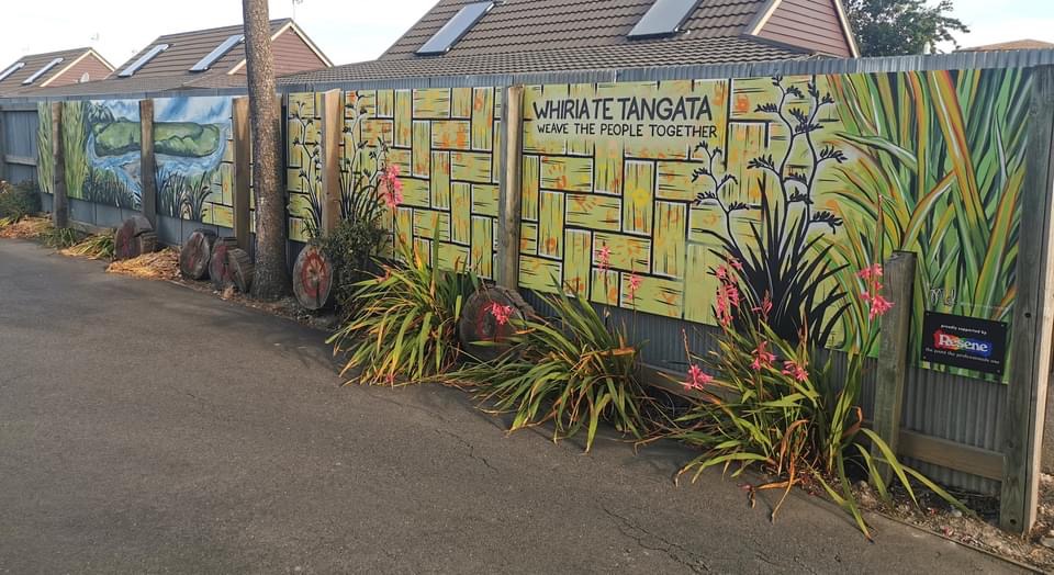 Weaving Together mural — wide view of the finished basketweave panels along the fence