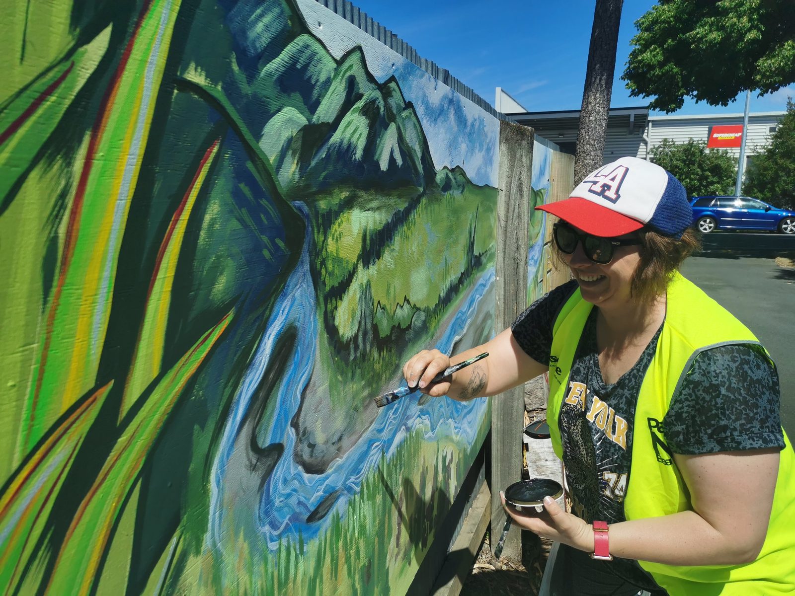 Weaving Together mural in progress — Mel and a helper painting flax detail onto a panel