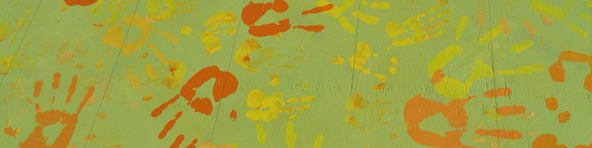 Off The Wall community mural work — colourful children's handprints in orange and yellow over a green background