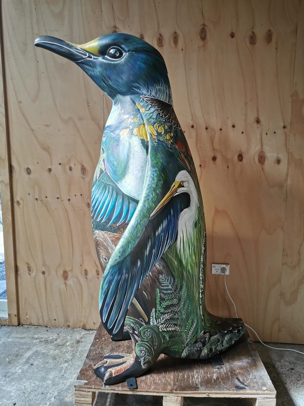 Birds of a Feather — the painted penguin sculpture viewed from a different angle in the workshop