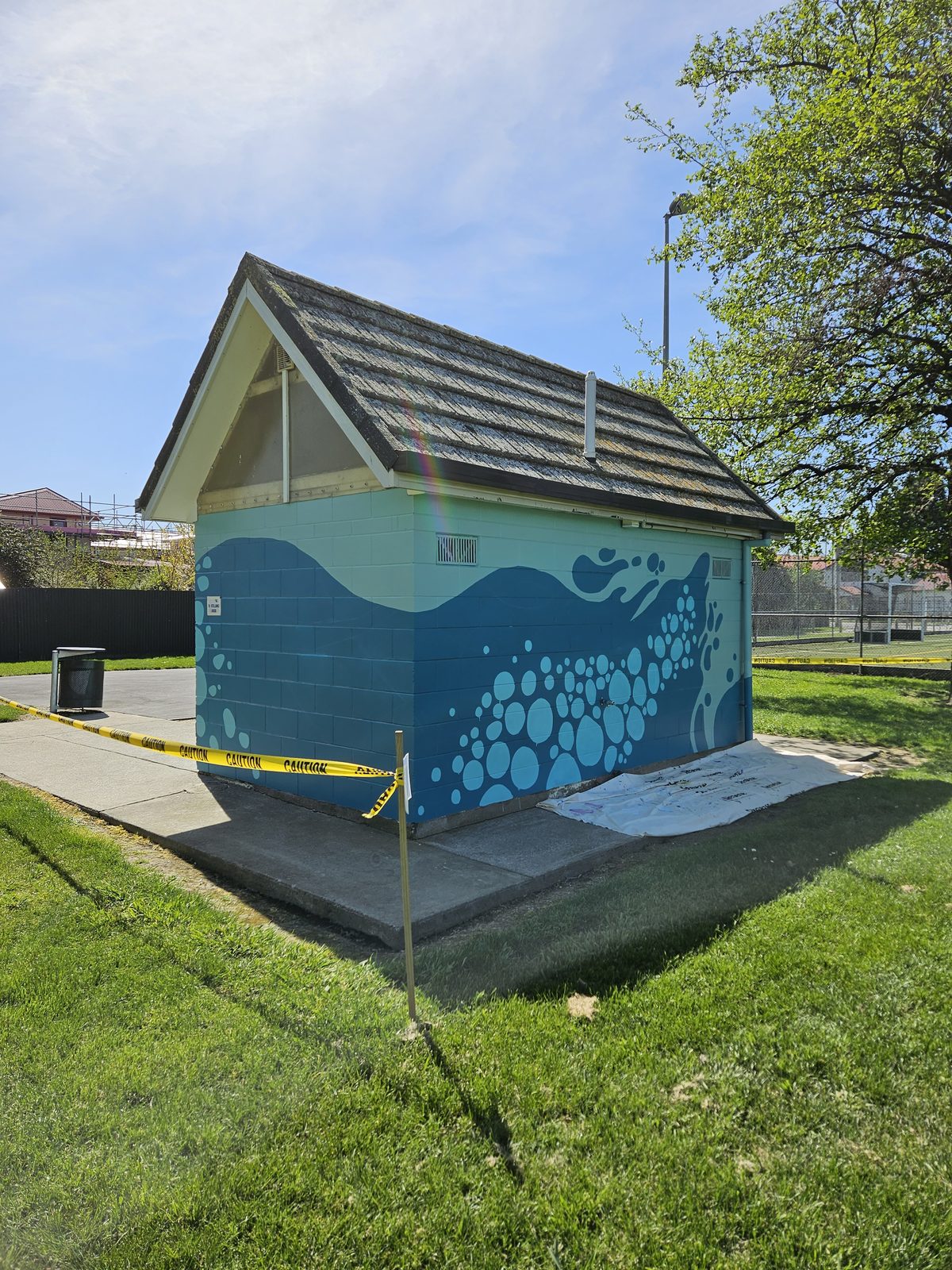 Flowing With Whio mural in progress — blue base coat blocked in on one side of the building