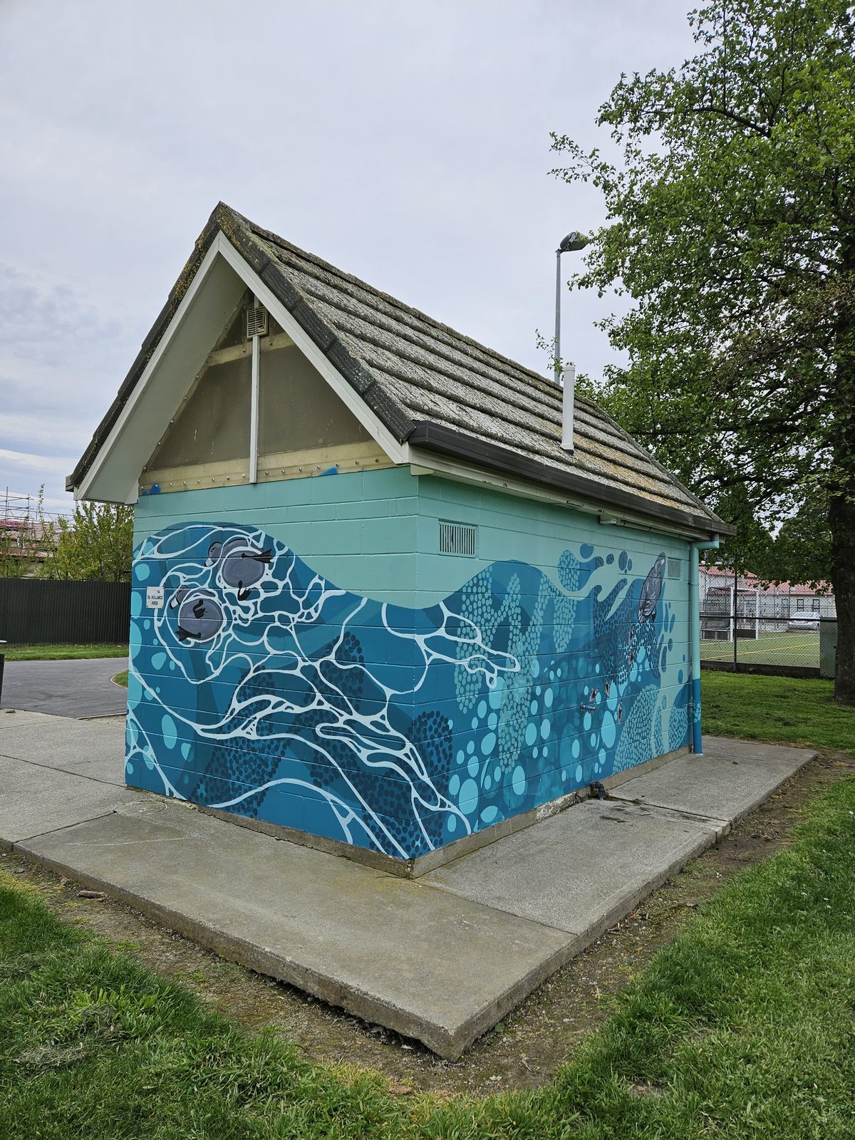 Flowing With Whio mural — one side of the building finished with the blue whio wave design