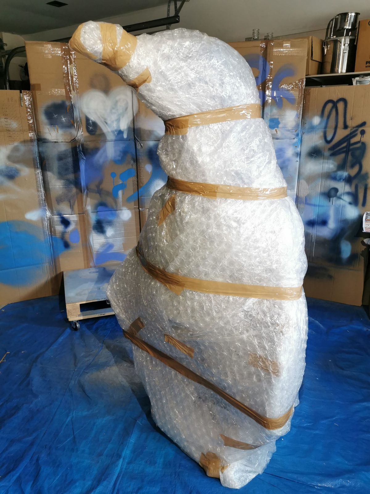 Ice sculpture in progress — sculpture partly wrapped in plastic with blue paint visible