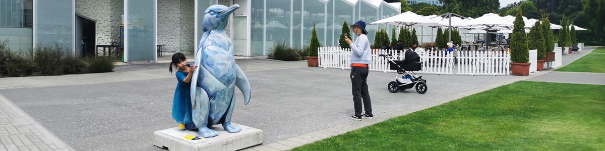 Ice sculpture — the faceted blue and silver penguin sculpture on display outdoors, with visitors stopping to view it