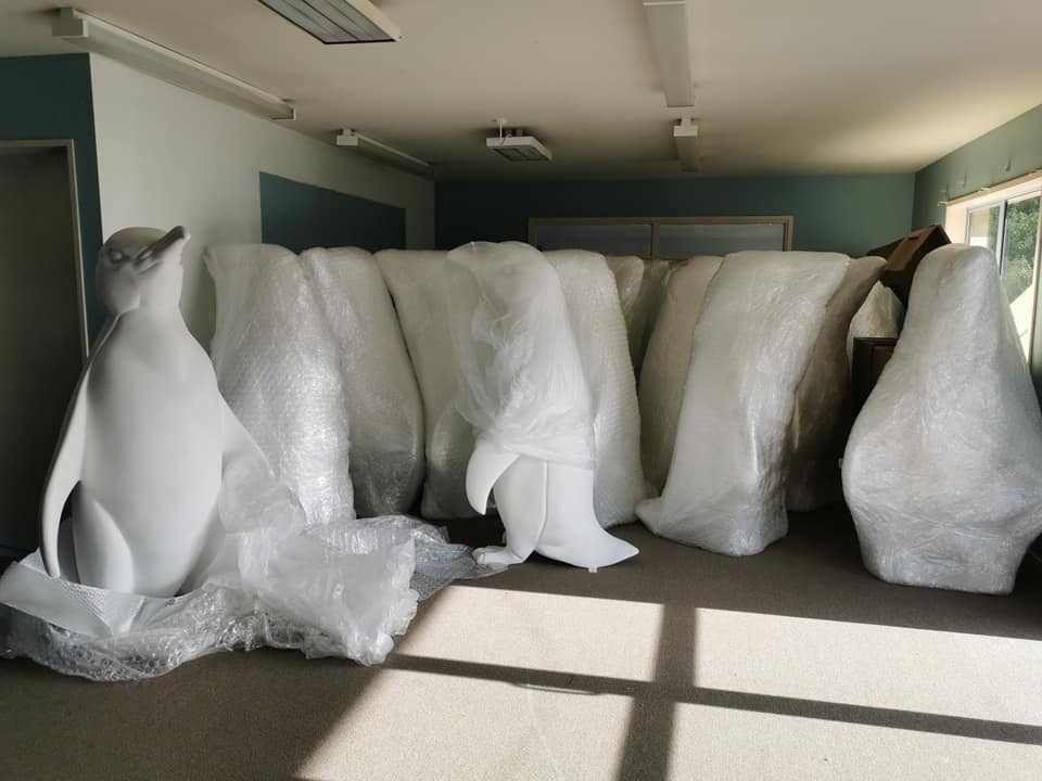 Several blank white penguin sculptures stacked together in the workshop before painting