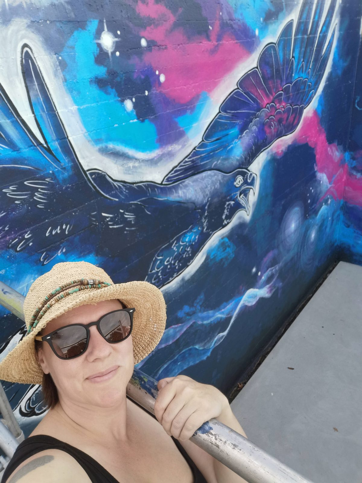 In Our Hands — Mel in a sunhat and sunglasses in front of the finished mural