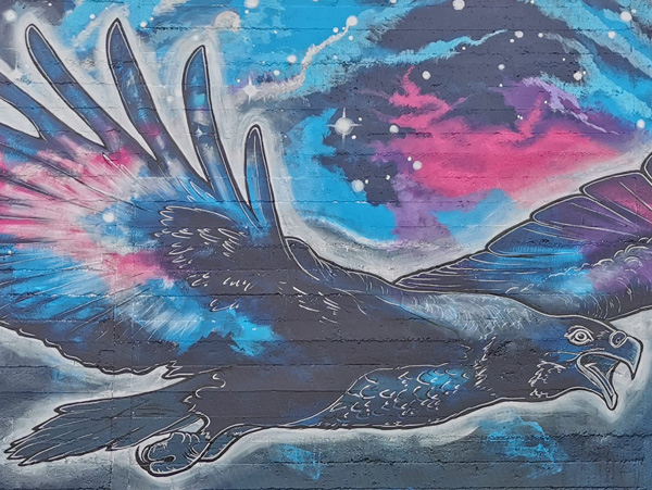 In Our Hands mural detail — Haast eagle in flight painted in blue and pink galaxy tones, Rangiora carpark