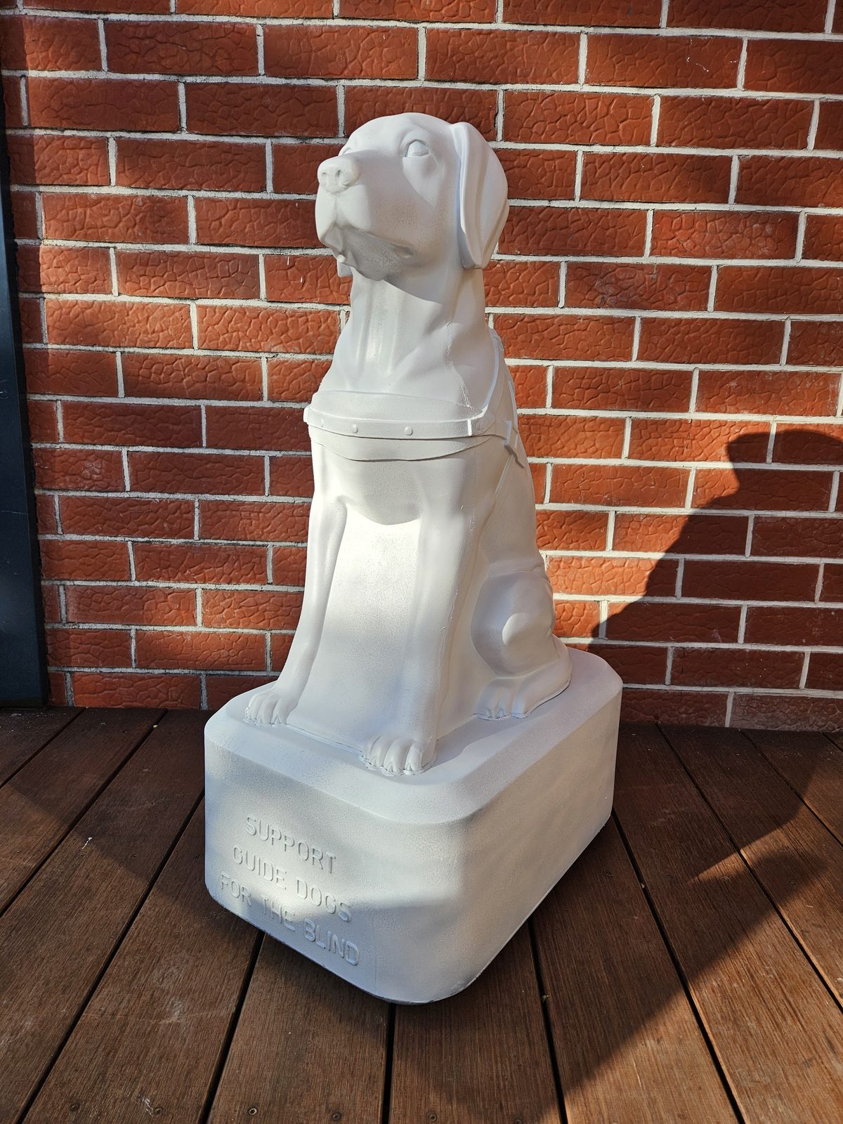 Louis Braille sculpture — blank white dog sculpture before painting, against a brick wall