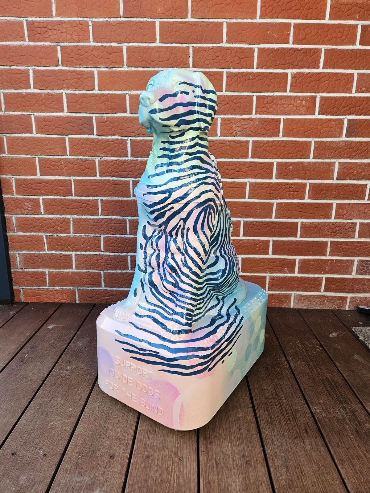Louis Braille sculpture — finished striped design against a brick wall