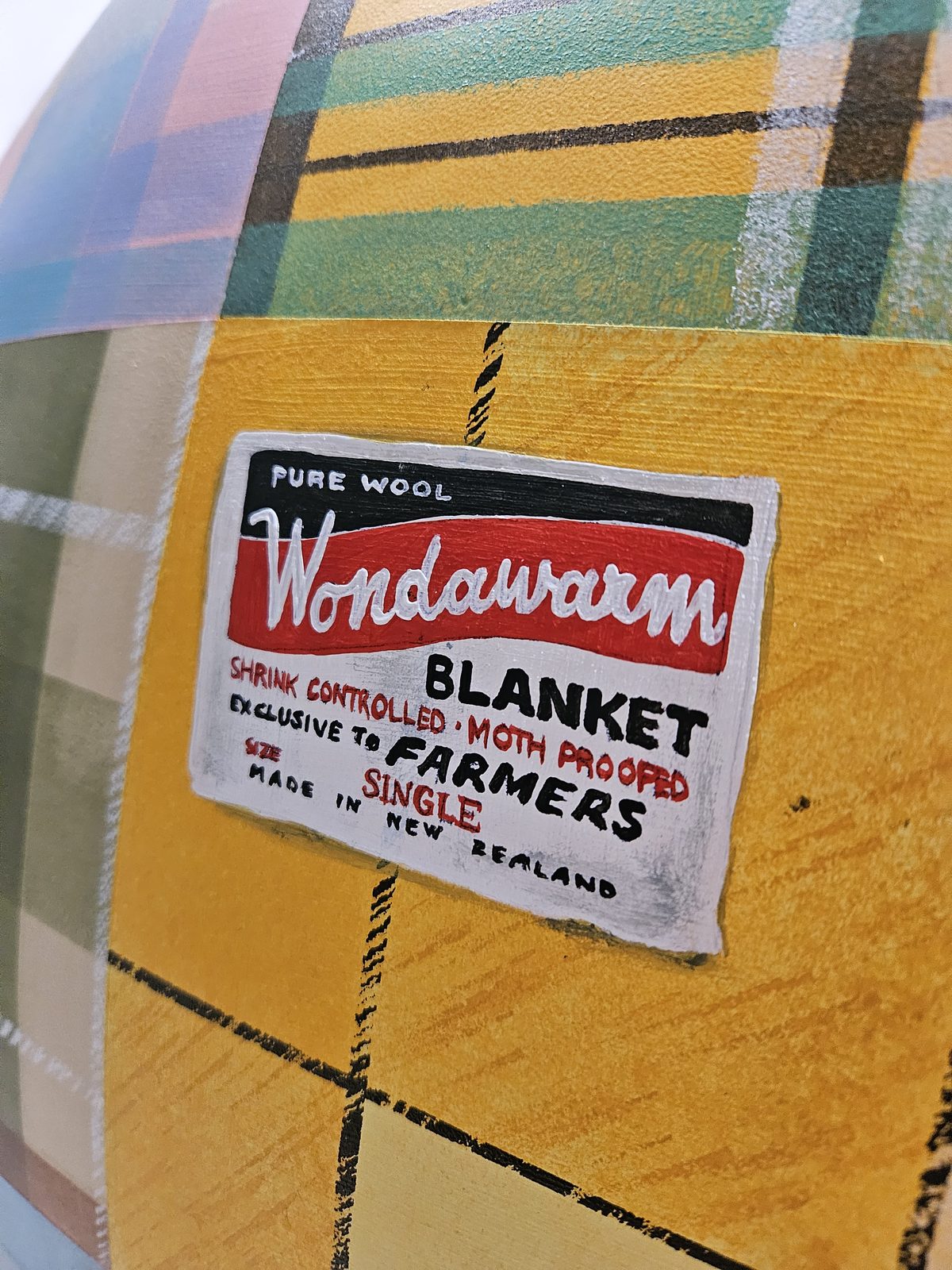 Mammoth Wolley sculpture detail — close-up of a wool mill branding label on the patchwork