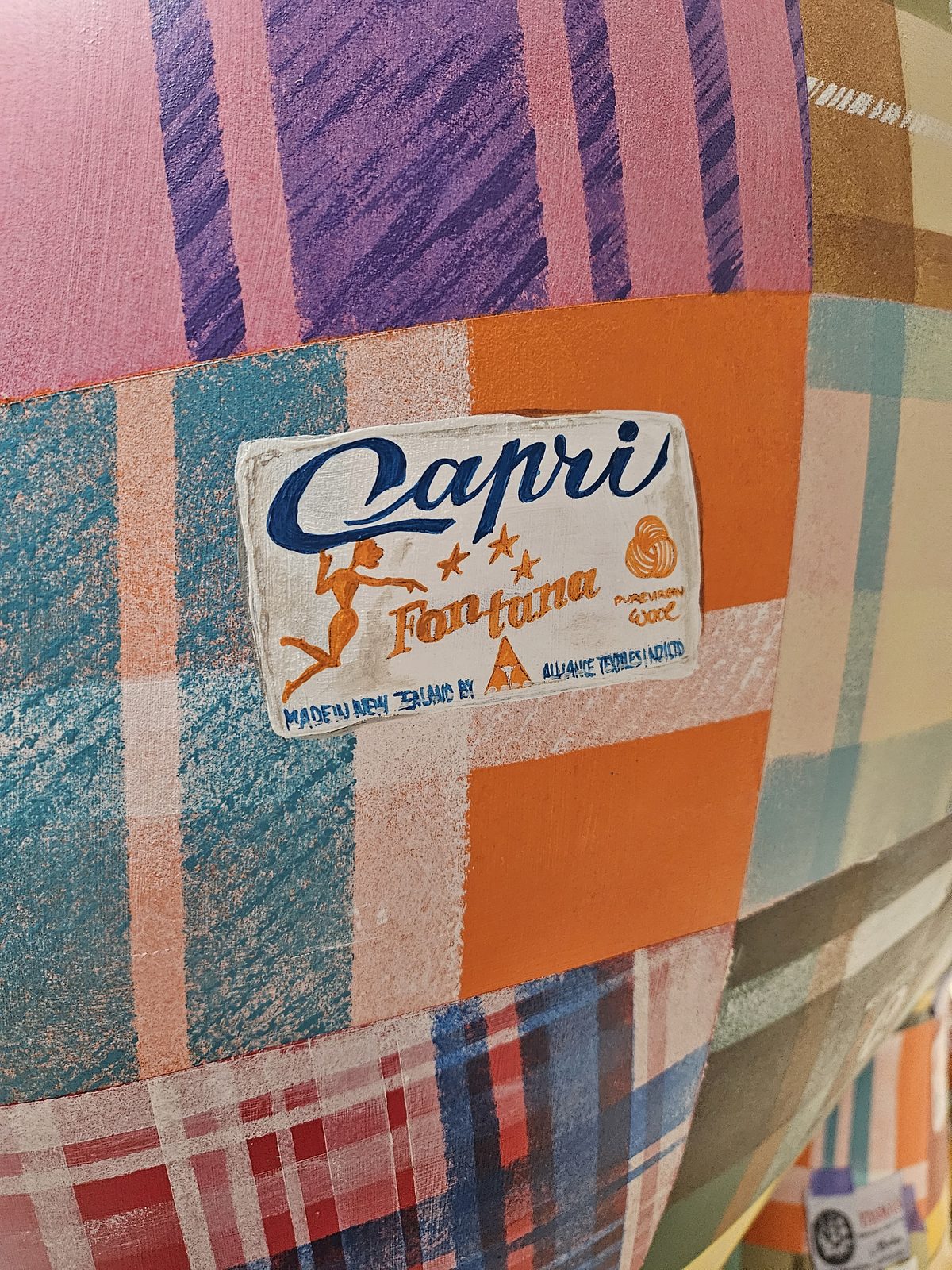 Mammoth Wolley sculpture detail — close-up of a Capri-branded wool label on the patchwork
