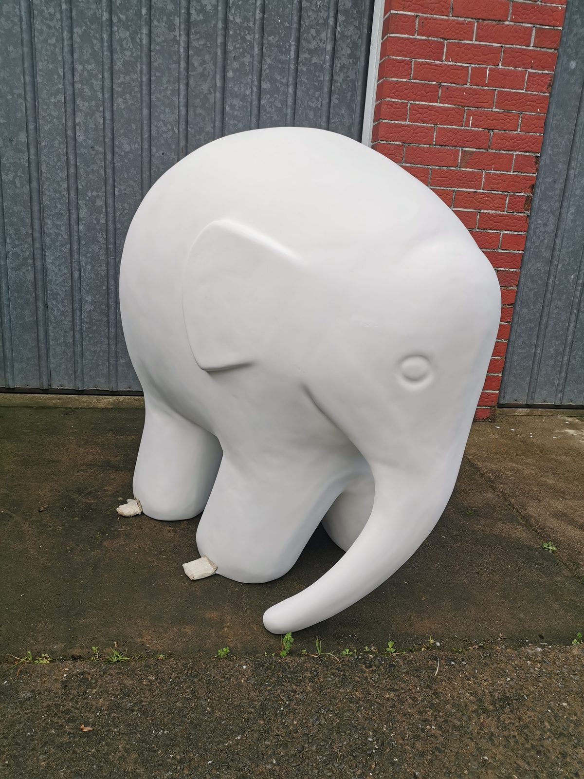 Mammoth Wolley sculpture — blank white elephant sculpture before painting, against a brick wall