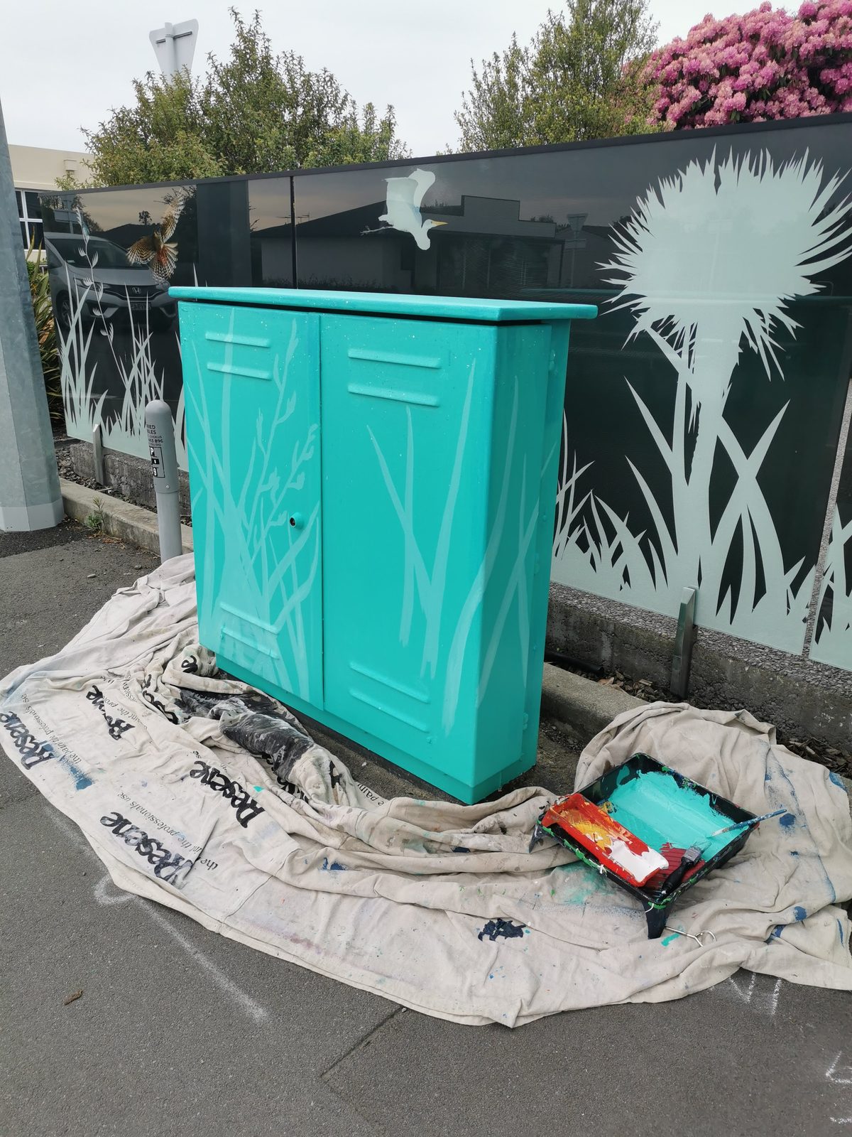 Tui Song mural in progress — teal primer coat applied to the cabinet