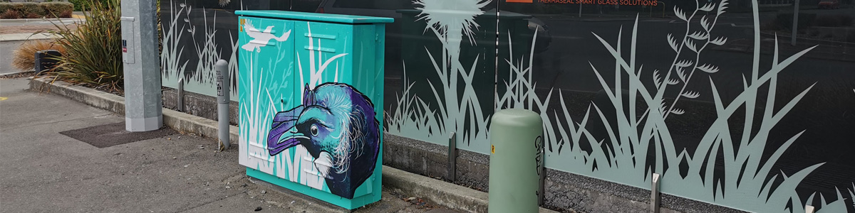Tui Song mural — the painted tui on the teal Chorus cabinet alongside silhouette flax and grass decals on the glass wall behind