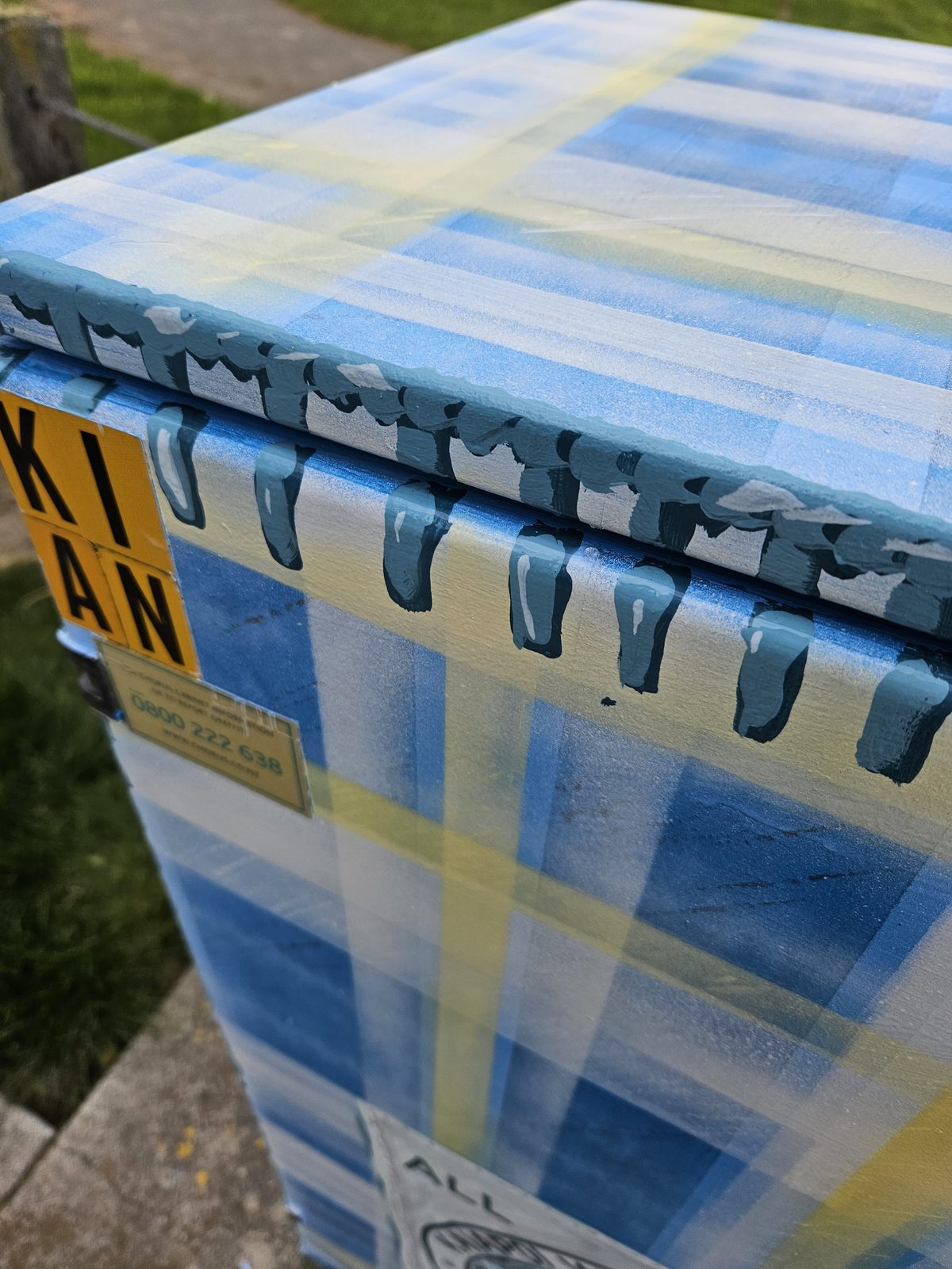 Woven History mural detail — close-up of the yellow and blue tartan pattern on the cabinet's edge